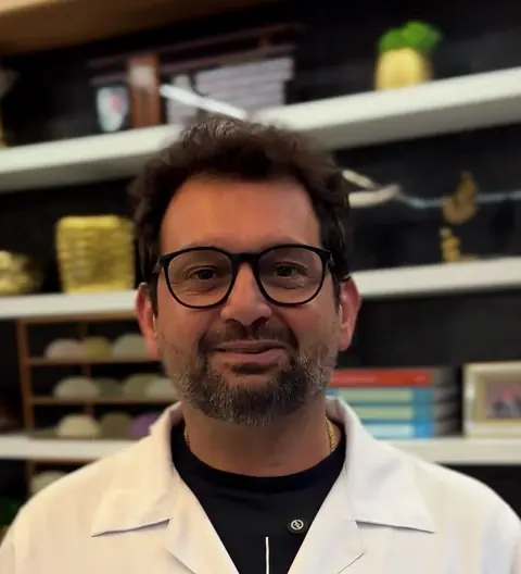 Dr. Fabrício Alam de jaleco com o monograma do Instituto, no consultório